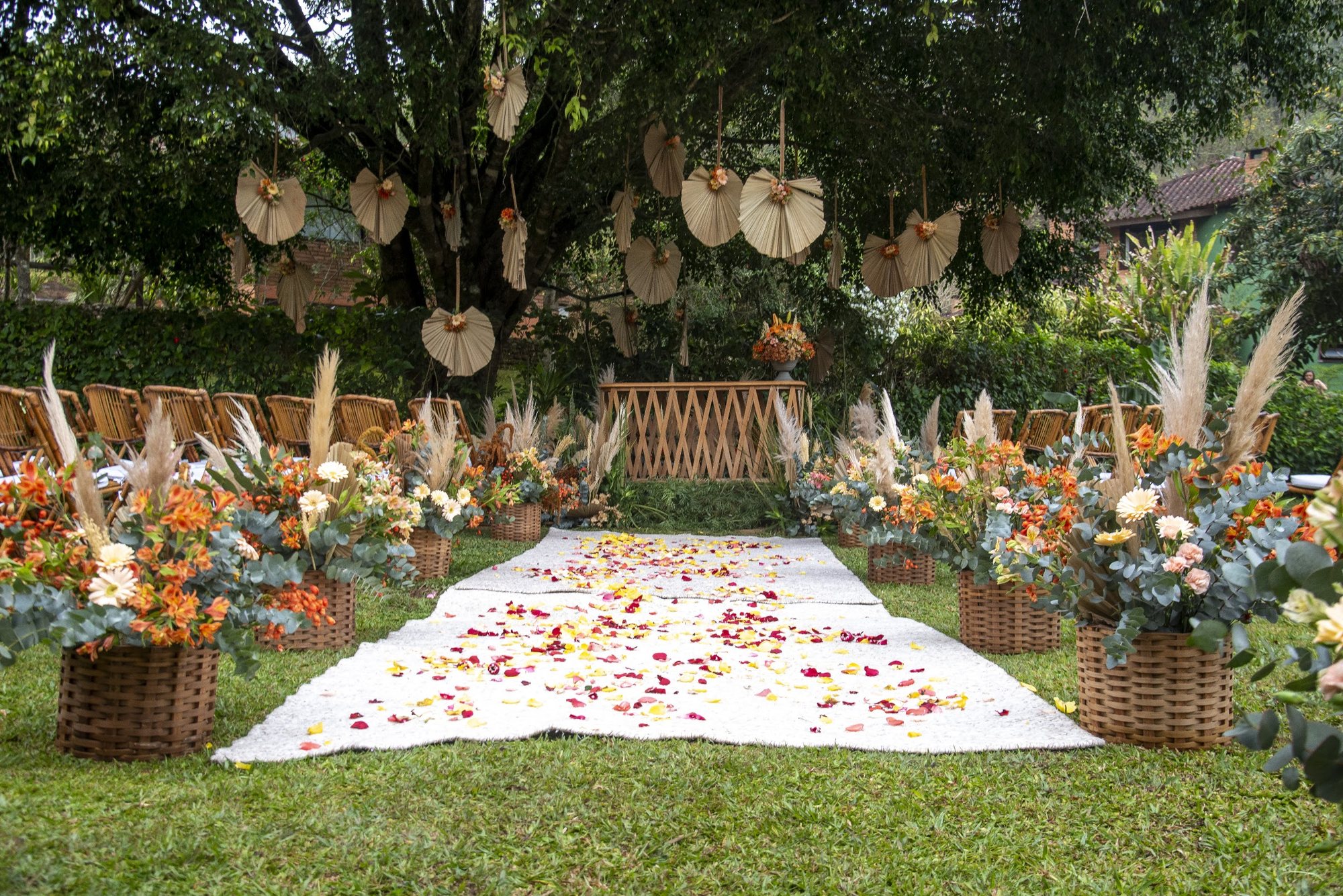 Cerimônia montada no jardim com caminho de pétalas e arranjos de flores