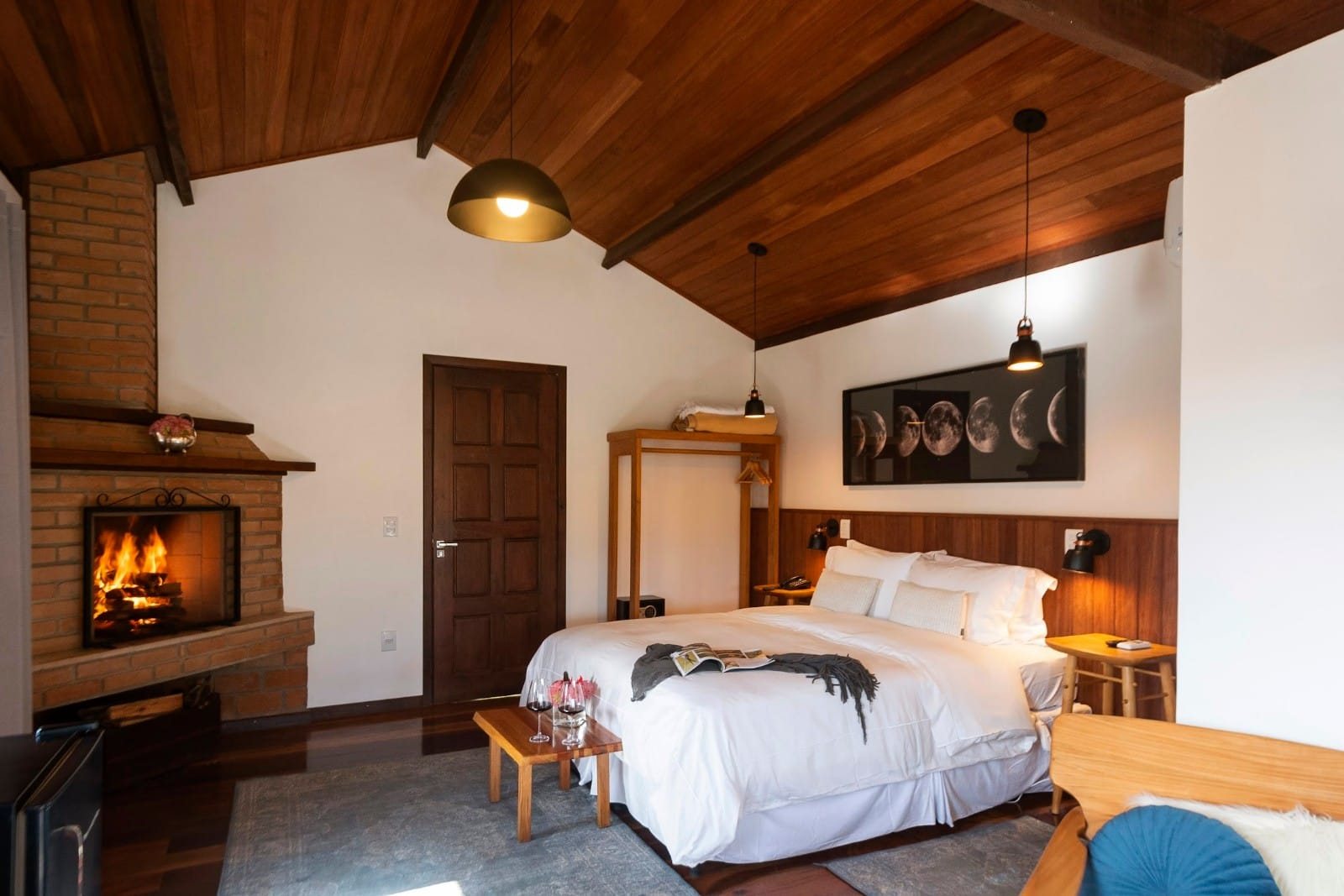 Quarto do chalé com cama de casal e lareira acesa